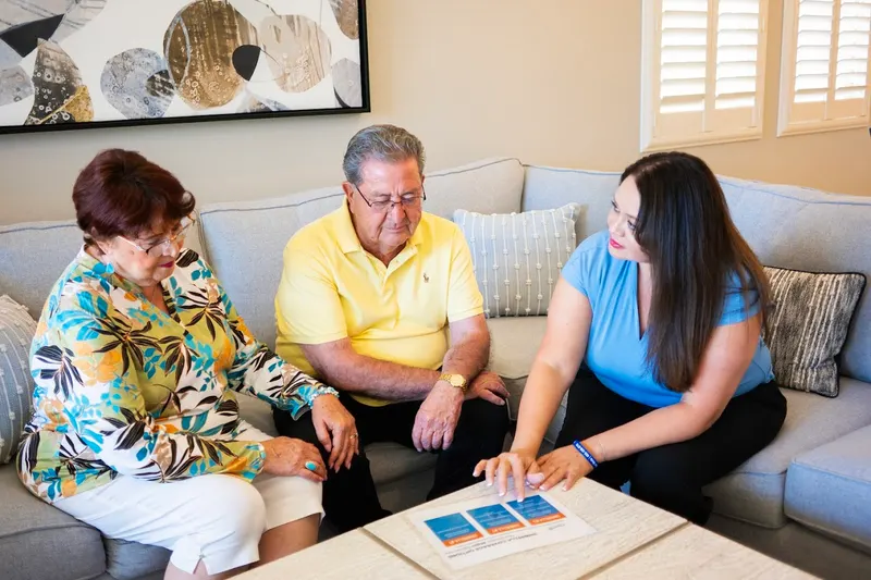 Viola Lucero comparing plan papers with a couple on their sofa